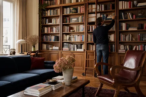 Illustration éditoriale : Lecteur choisissant un ouvrage dans une bibliothèque personnelle en bois